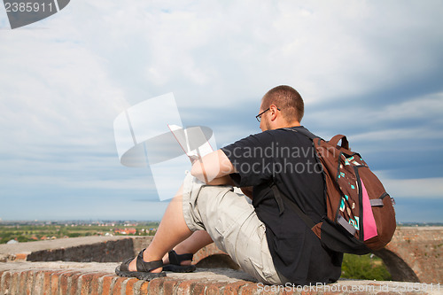 Image of Young man sitting outdoors and meditating