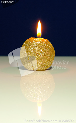 Image of Golden burning candle against blue background