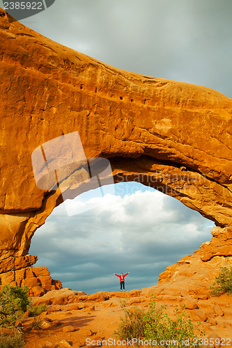 Image of Woman staying with raised hands inside an Arch
