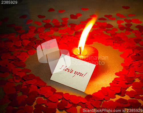 Image of Burning heart shaped candle and a card