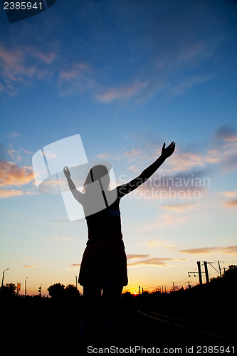 Image of Woman staying with raised hands