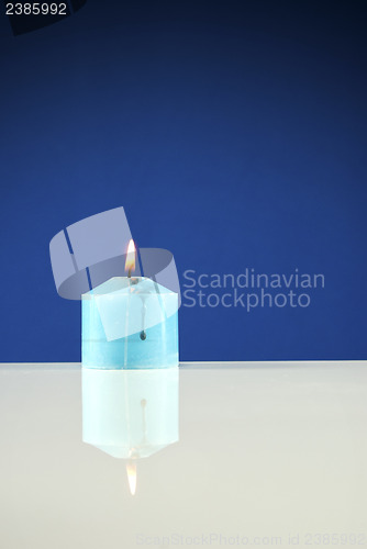 Image of Close up of burning candle against dark blue background