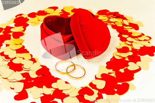 Image of Two rings in front of a red heart shaped box