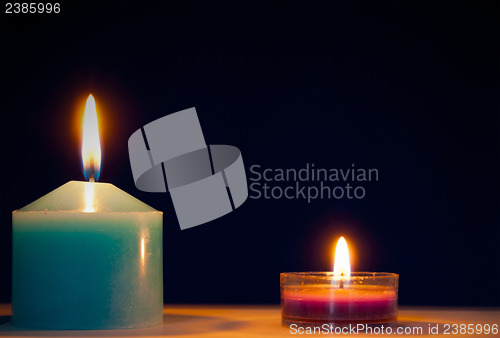 Image of Two burning candles against dark blue background