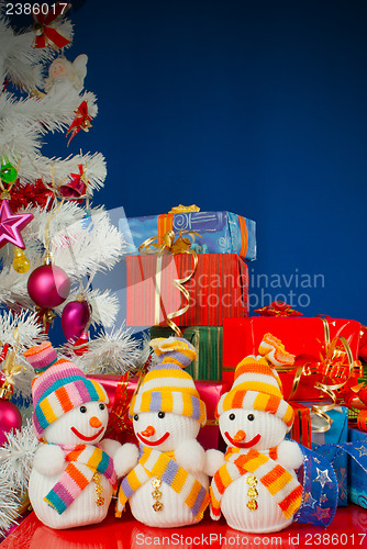 Image of Three snowmen in front of the Christmas presents over the blue b