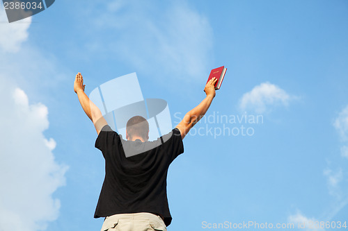 Image of Young man staying with raised hands