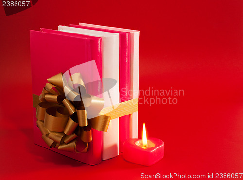Image of Row of books tied up with ribbon and burning candle