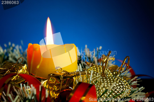 Image of Burning candle with Christmas decorations against blue background