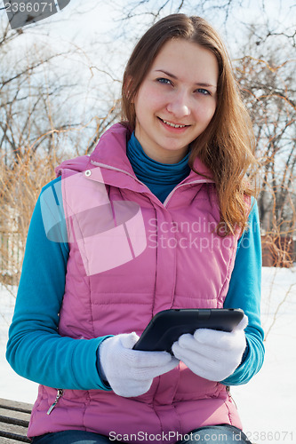 Image of Teen girl with e-book reader in a park