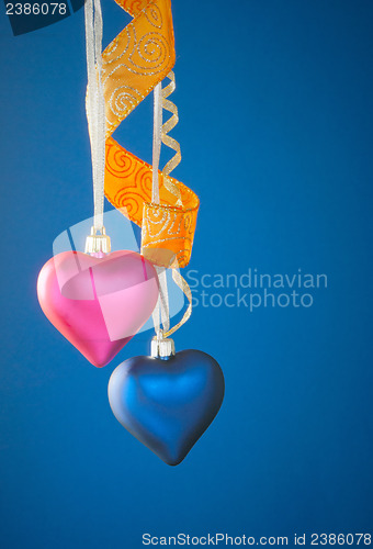 Image of Two heart shaped toys hanging against blue background