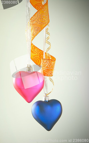 Image of Two heart shaped toys hanging against light background