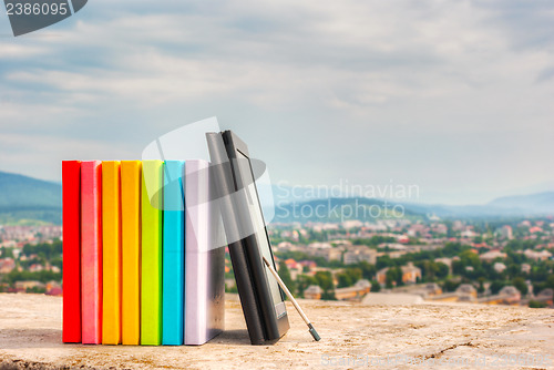 Image of Stack of colorful books with e-book reader