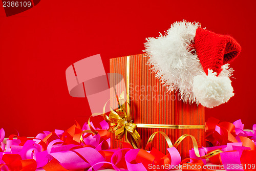 Image of Christmas present with Santa's hat against red background