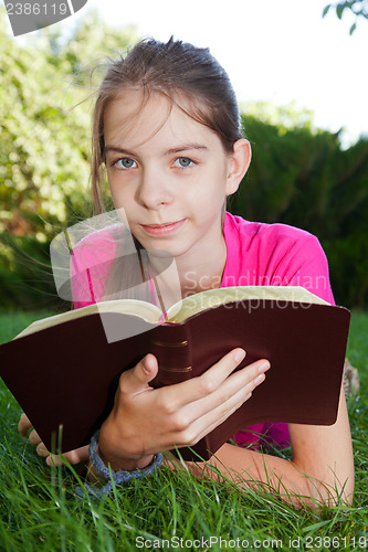 Image of Teen girl reading the Bible outdoors