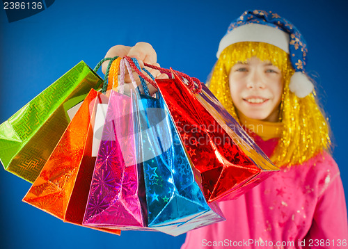 Image of Teen girl holds a variety of colorful bags against blue background