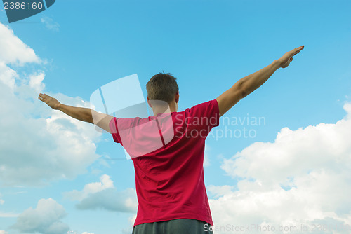 Image of Young man staying with raised hands