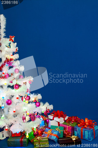 Image of Heap of the Christmas presents under decorated white evergreen t