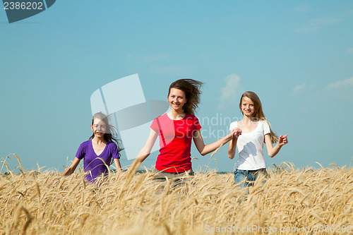 Image of Teen girls running at the wheat field