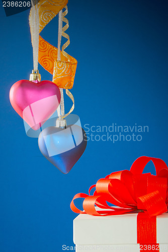 Image of Two heart shaped toys hanging against blue background