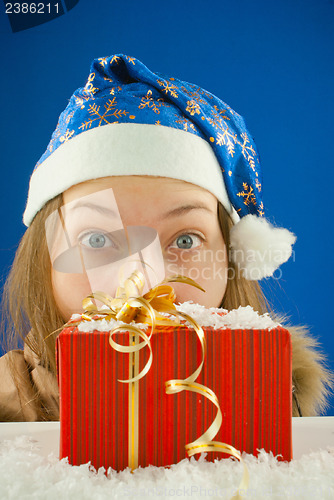 Image of Surprised teen girl looking from behind the Christmas present