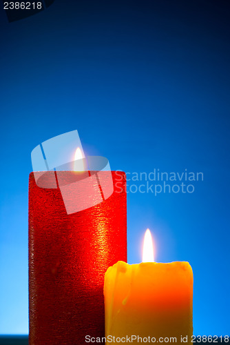 Image of Five burning colourful candles against blue background