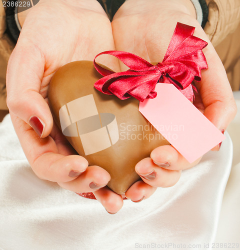 Image of Hands holding a heart shaped chocolate candy 