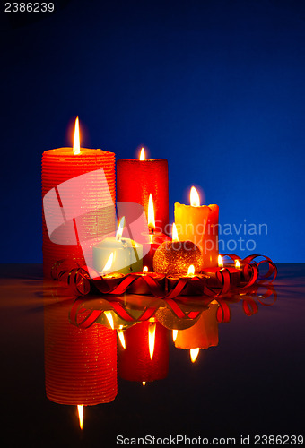 Image of A lot of burning colorful candles against black background