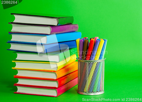 Image of Stacks of colorful books and socket with felt pens