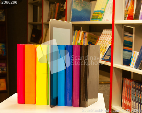 Image of Row of colorful books and tablet PC reader in the book shop