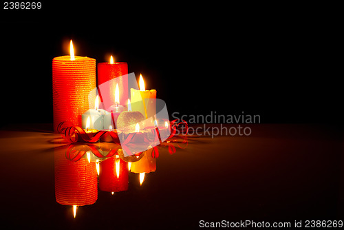 Image of A lot of burning colorful candles against black background