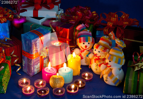 Image of Three snowmen in front of the Christmas presents and burning can