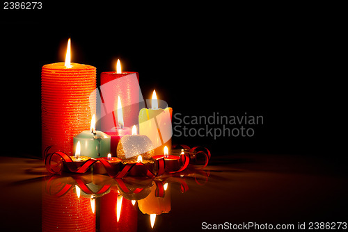 Image of A lot of burning colorful candles against black background