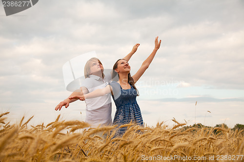 Image of Couple staying with raised hands at sunset time