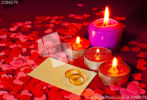 Image of Two rings and a card with marriage proposal with four candles