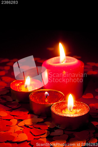 Image of Four burning candles over red background