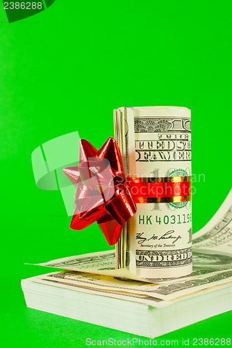 Image of Roll of US dollars tied up with ribbon on the stack of bills