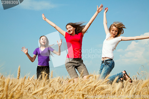 Image of Teen girls jumping at a wheat field