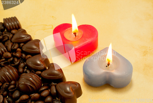 Image of Two burning heart shaped candles and candies