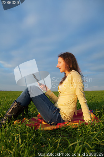 Image of Teen girl reading electronic book outdoors