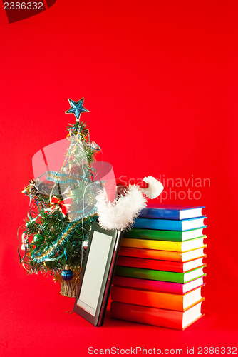 Image of Electronic book reader with stack of books against red background