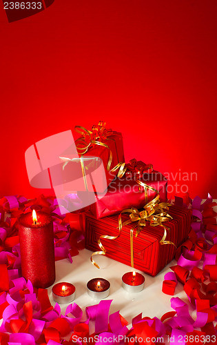 Image of Christmas gifts and candles over red background