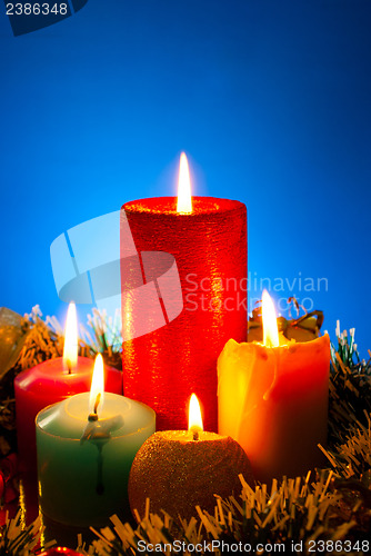 Image of Five burning colourful candles against blue background