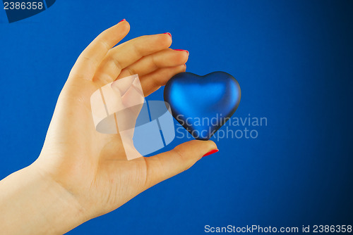 Image of Hand holds a heart shaped gift against blue background