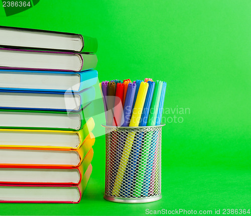 Image of Stack of colorful books and socket with felt pens