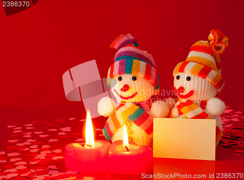 Image of Three snowmen with two burning heart shaped candles