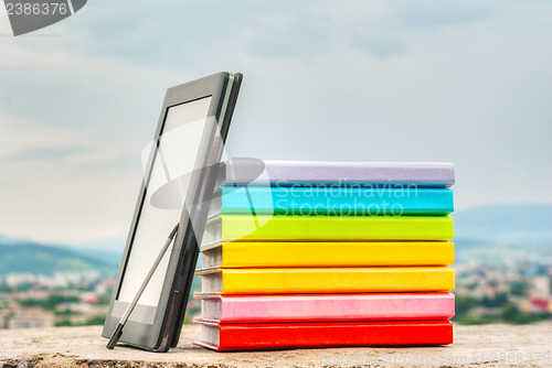 Image of Stack of colorful books with electronic book reader