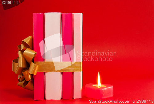 Image of Row of books tied up with ribbon and burning candle