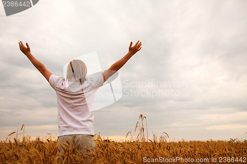 Image of Young man staying with raised hands at sunset time