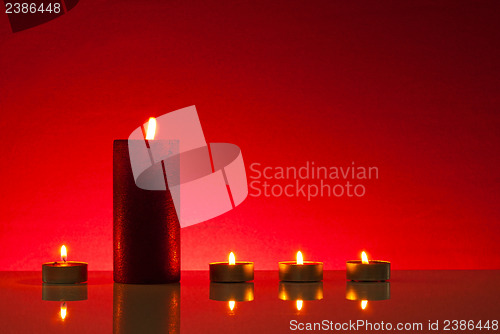 Image of Five burning candles over red background