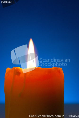 Image of Close up of a burning candle against blue background